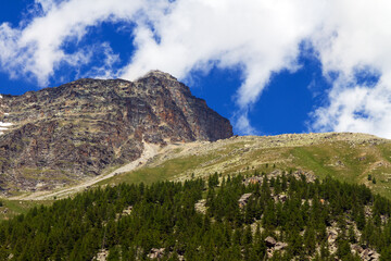 Alpine mountains against the blue sky with clouds in Italy