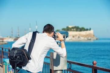 A tourist is watching trough a coin-operated binoculars in Kusadasi, Turkey