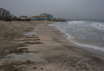 A close look at a deserted beach with a pile of rocks, concrete columns, and a sand embankment.  Pomorie resort, Bulgaria