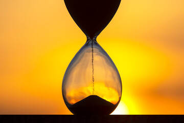 Hourglass counts the length of time against the background of the evening sun