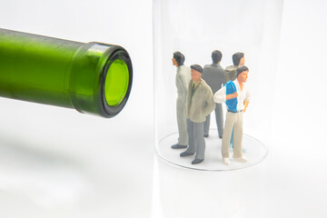 miniature people. man addicted to alcohol on the background of a bottle of wine and a glass. the...