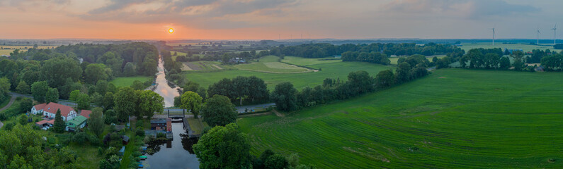 Summer sunset over river in countryside landscape. Lock at Kluvensiek of the Old Eider Canal,...
