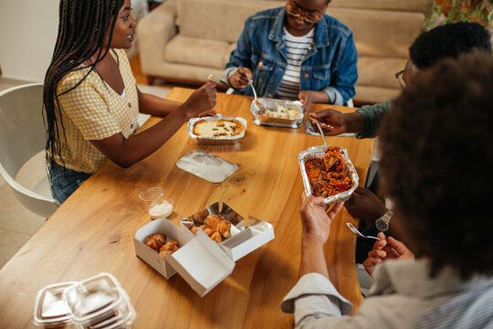 Group Of Young Adults Eating Takeout Food At Home