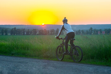 Obraz premium cyclist on bike rides along the fields of wheat in the sunlight. sports and hobbies. outdoor activities