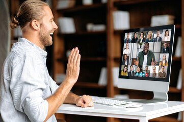 Virtual meeting, brainstorm of colleagues, online conversation. Positive caucasian, american young man greets interlocutors, talks on video call with multiracial business group, discussing the project