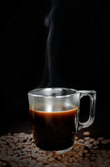 a cup of coffee on a black background with grains. Selective focus