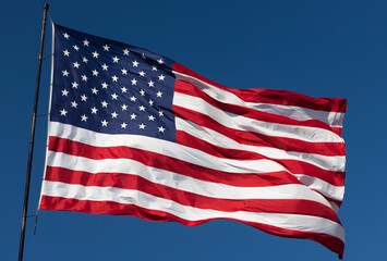 American Flag Waving In Wind Against a Deep Blue Sky.