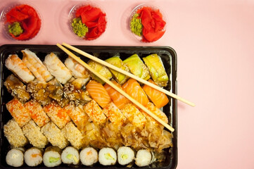 Asian food - set of rolls on a pink background in dishes for delivery. High quality photo