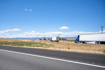 Big rigs semi trucks with different semi trailers standing on the highway exit road take a break...