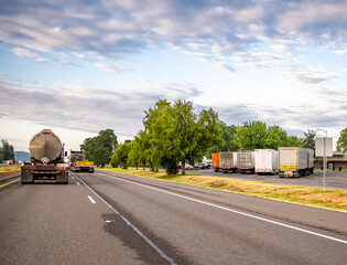 Big rigs semi trucks with semi trailers running on the road and standing for break on the rest area...