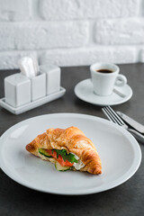 Delicious brunch, breakfast - coffee and croissant sandwich with cream cheese, salmon