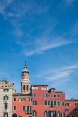 Venetian houses and tower under blue sky in Venice, Italy