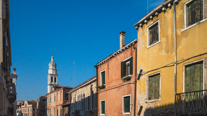 Venetian houses and tower under blue sky in Venice, Italy