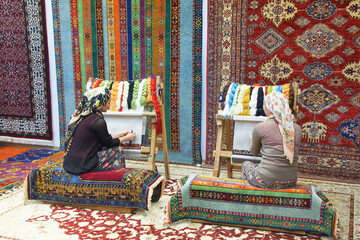 Loom for hand weaving carpet with woman working at backstage
