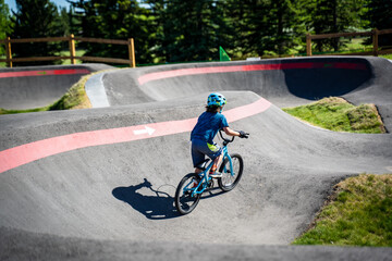 A young child rides the new South Glenmore Park BMX pump track on his bike on a summer evening in...
