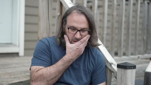 Depressed-looking man looking upset outside sitting on staires.