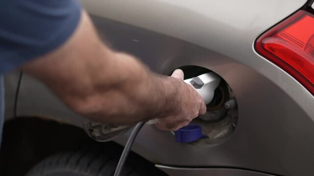 Humoristic clip of a man trying to plug an electric car charger into a gas-powered car. It doesn't fit and the man is wondering why.