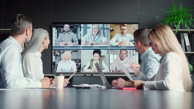 Global corporate online videoconference chat in meeting room with diverse people talking in modern office and multicultural multiethnic colleagues on big screen monitor. Business technologies concept.