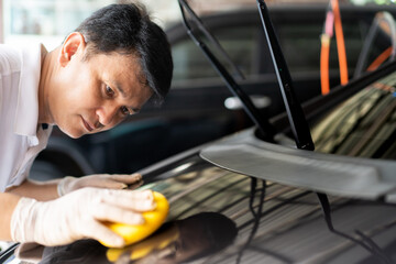 Asian skillful and professional service man polishing and detailing on a car body.