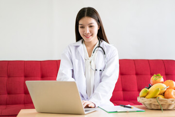 Happy Asian nutritionist working in her office in hospital.