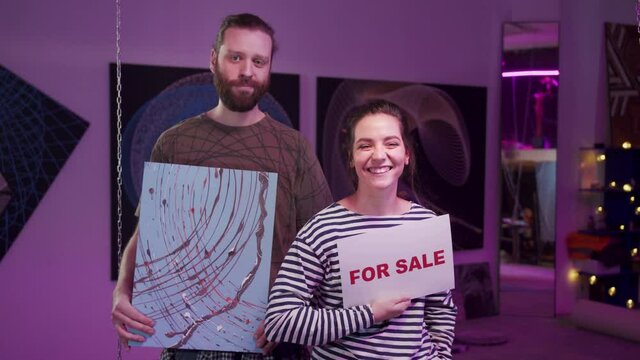 Young painters are showing a picture for sale 