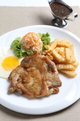 grilled golden bbq meat chicken cop pork cutlet beef steak with fried egg, French fries, coleslaw salad and black pepper sauce in pot western cuisine menu