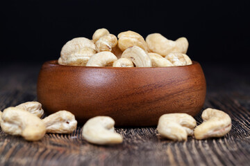 cashew nuts on an old wooden table and in a wooden bowl