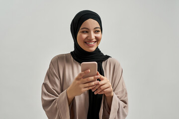 Cheerful young arabic woman in hijab looking to side