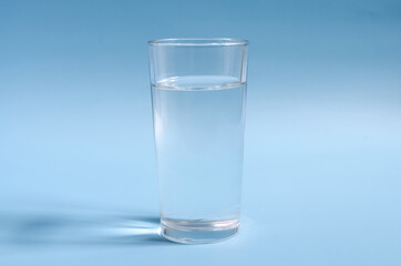 A glass of clear water on a blue background close-up. A glass of water on a colored background