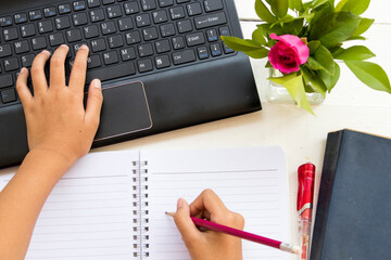 hand of student girl writng work with computer, notebook and dictionary arrangement flat lay style...