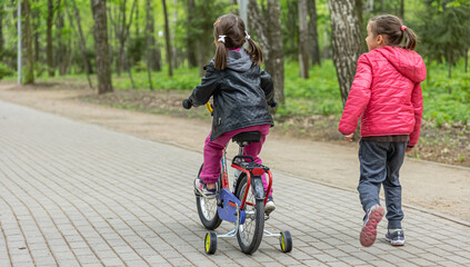 Children ride a bike for a walk in the park.