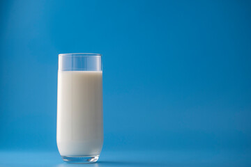 Glass of white milk isolated on blue background