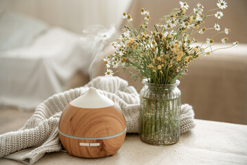 Cozy home composition with an air humidifier and wildflowers in a vase. - obrazy, fototapety, plakaty