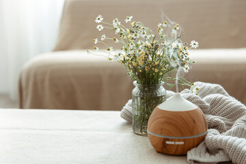 Cozy home composition with an air humidifier and wildflowers. - obrazy, fototapety, plakaty