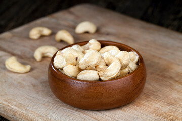 cashew nuts on an old wooden table and in a wooden bowl