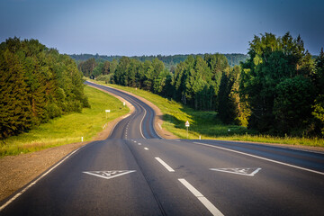 a wide asphalt road with new road markings passes through the picturesque area