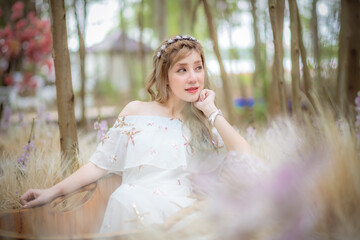 Portrait beautiful woman tourist posing happiness with smile ,she wearing a nice dress to travel in garden colorful flowers blooming for a summer vacation with beautiful flower garden background.