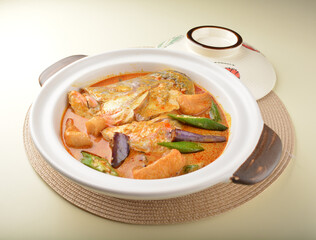 chef cook home style nyonya spicy curry grouper fish head with vegetables in big clay pot