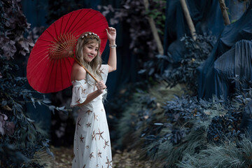 Asian woman holding a red umbrella in a mysterious forest