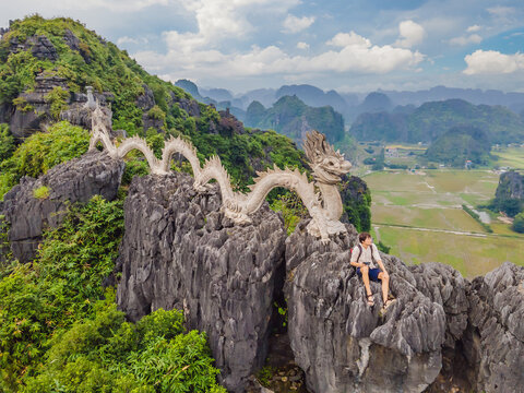 Male tourist on the background of Amazing huge dragon statue at limestone mountain top near Hang Mua view point at foggy morning. Popular tourist attraction at Tam Coc, Ninh Binh. Vietnam travel