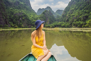 Woman tourist in boat on the lake Tam Coc, Ninh Binh, Viet nam. It's is UNESCO World Heritage Site, renowned for its boat cave tours. It's Halong Bay on land of Vietnam. Vietnam reopens borders after