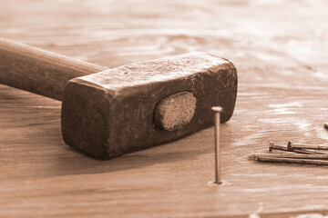 hammer and nails on the wooden surface one nail is hammered into the board