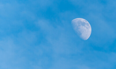 Half Moon in a Blue and Cloudy Sky in Daytime