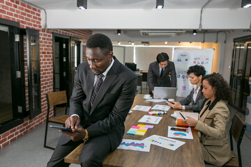 African business sitting and check his stock port folio confident in the office in front of his...