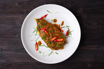 Close up view of Spicy Red Curry with crispy fried fish,  on white dish