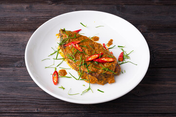 Close up view of Spicy Red Curry with crispy fried fish,  on white dish