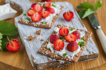 Snack or breakfast, rye crispbread with cream cheese, green onions and fresh strawberries on a...