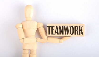 Wooden man shows with a hand to block with text TEAMWORK