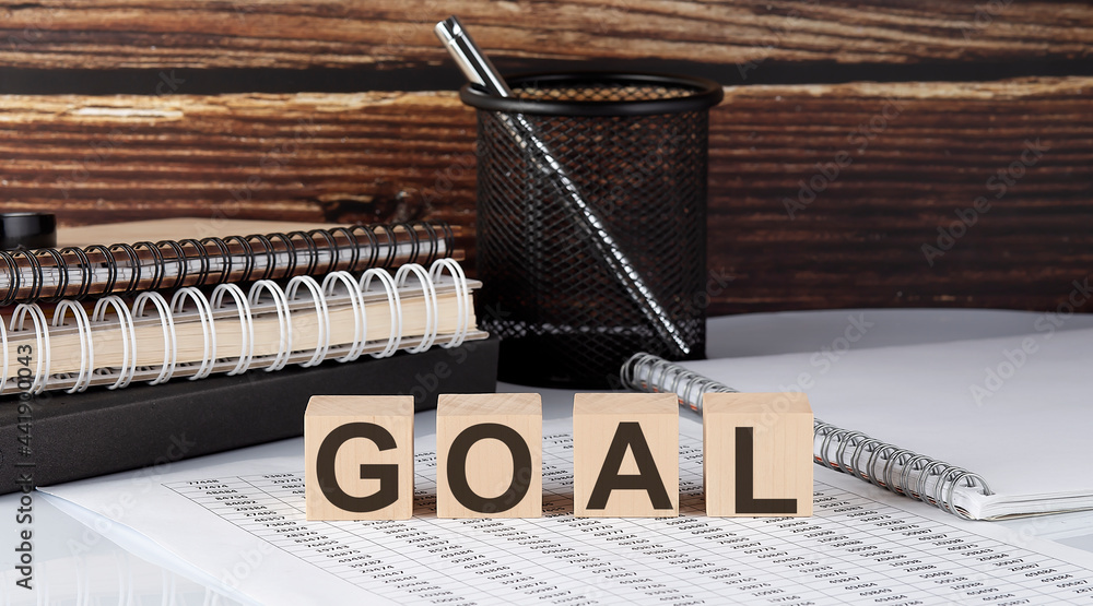 Poster goal text on the wooden block with notebooks on the chart