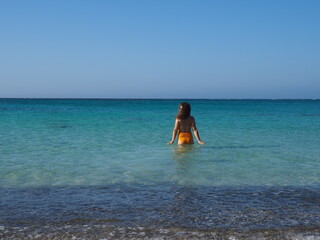 Jeune femme dans de l'eau turquoise sur une plage en Crète